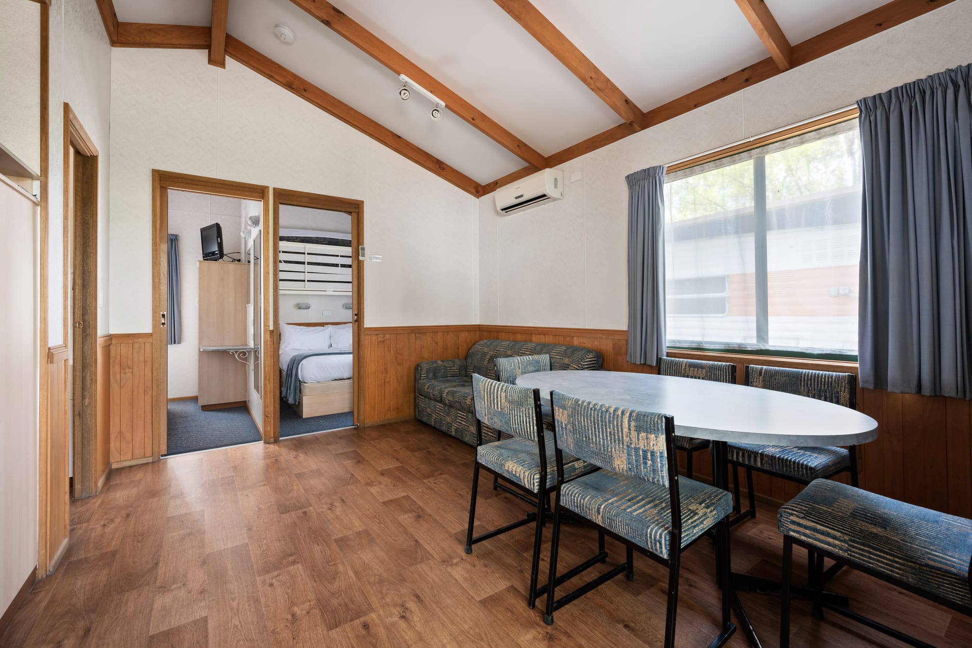 Spacious family cabin interior with dining area and timber beams at Bright Accommodation Park, Bright VIC