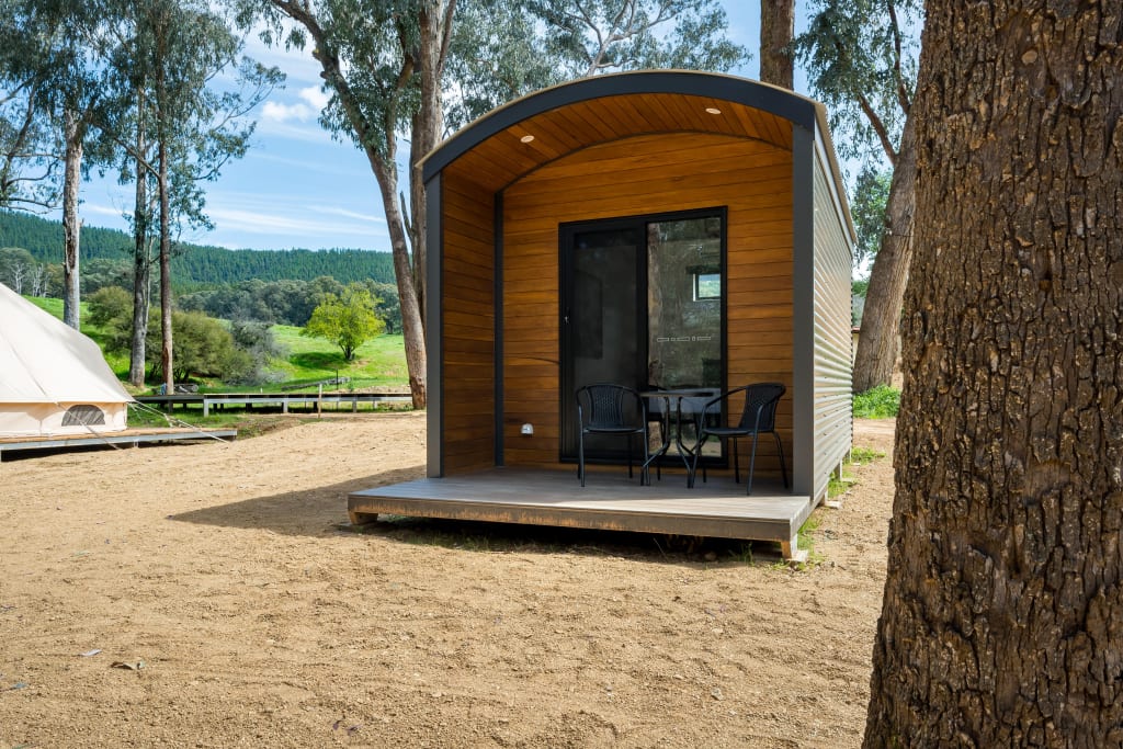 Modern glamping pod with covered deck at Bright Accommodation Park, surrounded by gum trees and mountain views