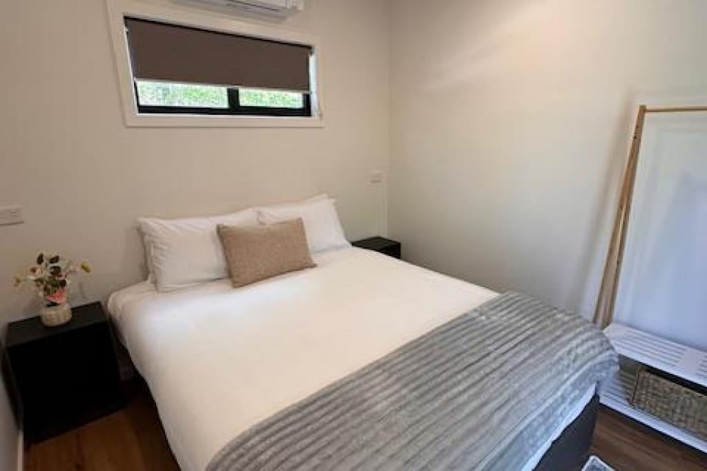 Modern bedroom with double bed and fresh white linens at Bright Accommodation Park in Bright, Victoria