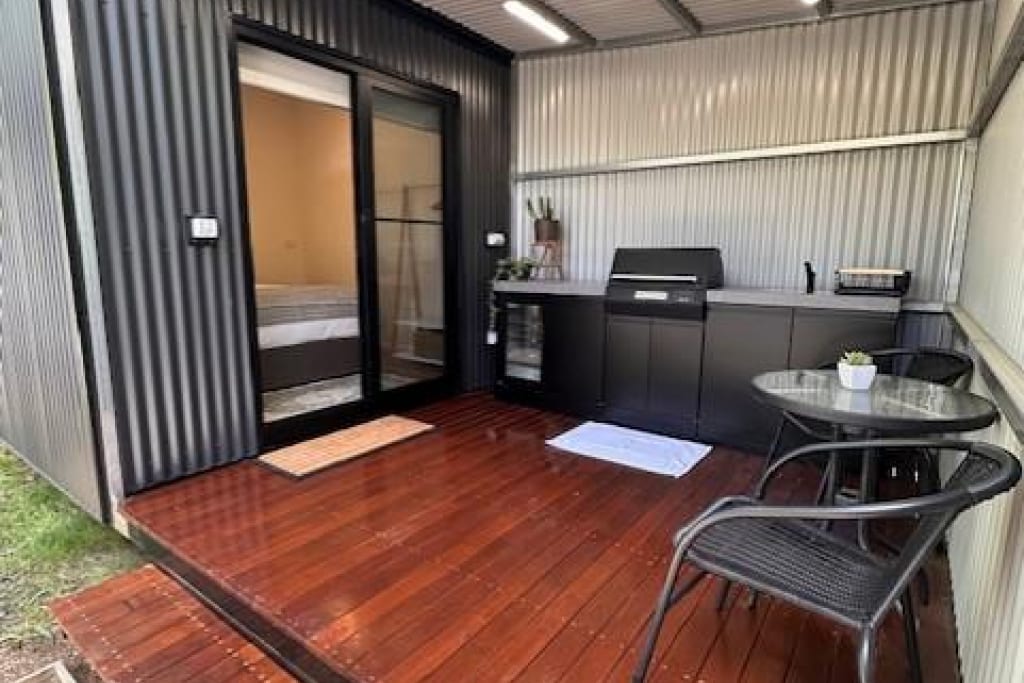 Covered timber deck with outdoor BBQ kitchen and dining area at Bright Accommodation Park, Bright VIC
