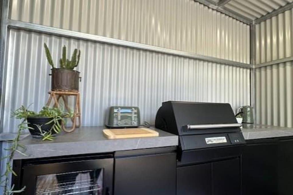 Modern covered BBQ area with gas grill and preparation space at Bright Accommodation Park