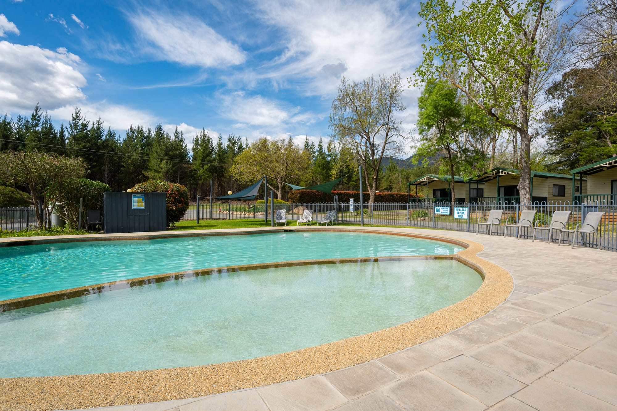 Outdoor swimming pool with sun loungers at Bright Accommodation Park, Bright VIC, surrounded by trees and mountain air