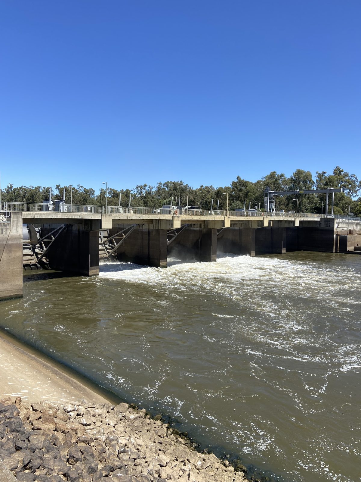 White water spilling from the weir gates down the concrete channel at Torrumbarry Weir Holiday Park