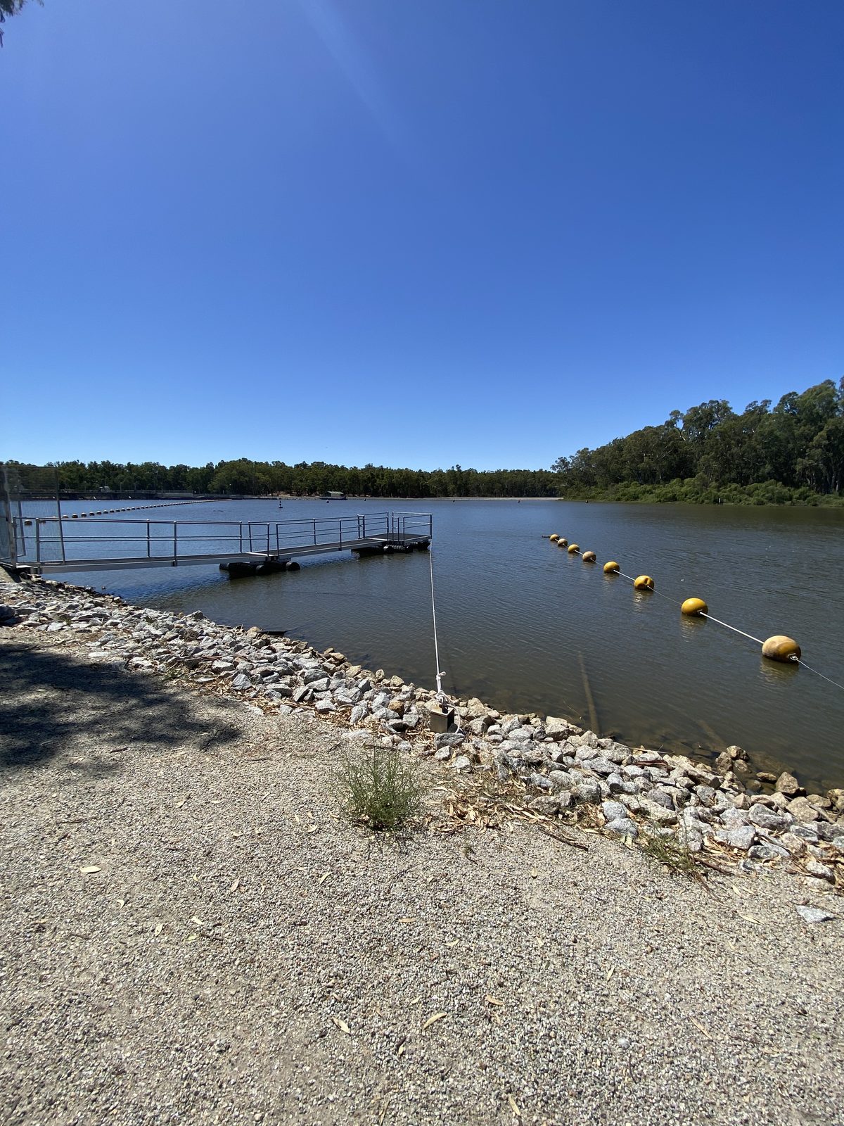 Rocky river edge with buoy line and jetty above the weir at Torrumbarry Weir Holiday Park