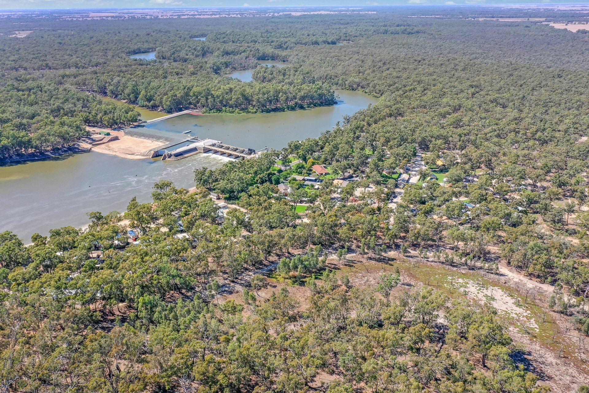 Wide aerial of park cabins and river surrounded by bushland at Torrumbarry Weir Holiday Park