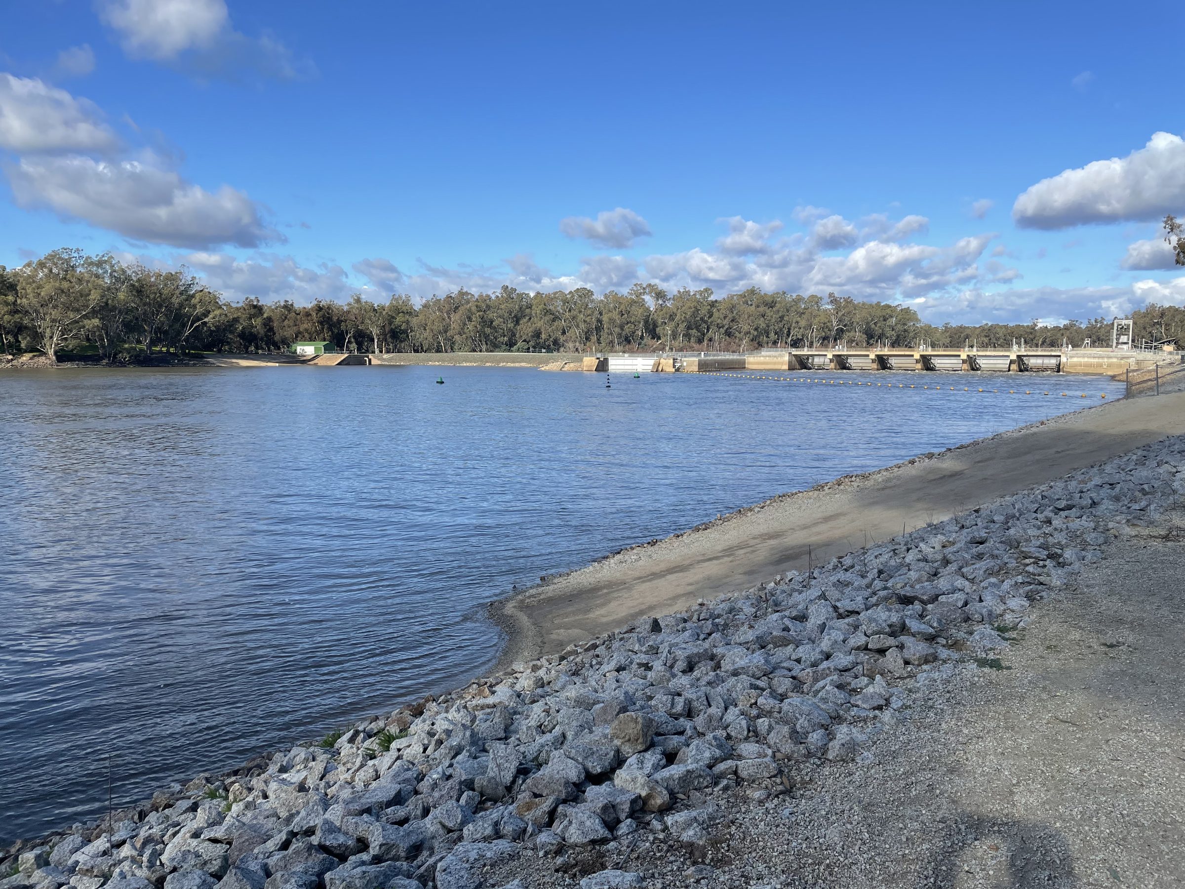 Torrumbarry Weir wall spanning the Murray River, seen from the rocky bank near Torrumbarry Weir Holiday Park, Patho VIC