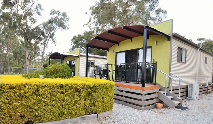 Lime green self-contained cabins with curved awning roofs and private deck at Torrumbarry Weir Holiday Park caravan park, Patho VIC