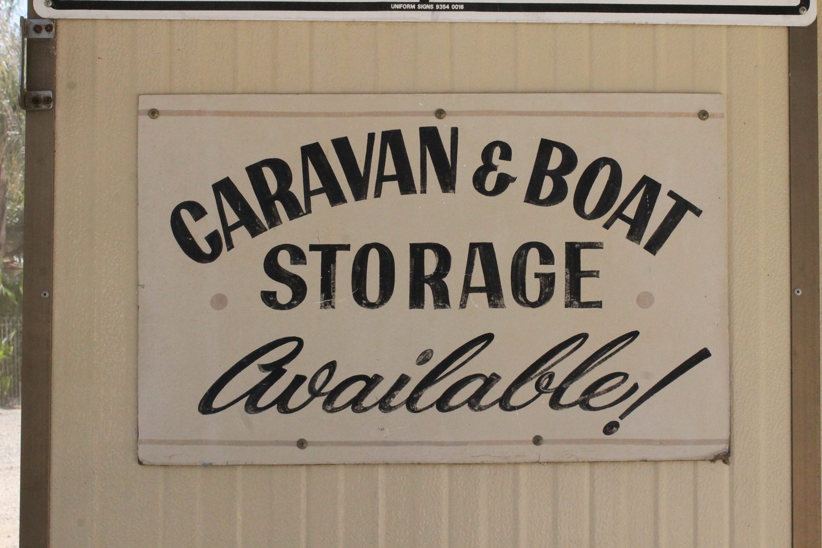 Hand-painted sign reading 'Caravan & Boat Storage Available!' on a shed wall at Torrumbarry Weir Holiday Park