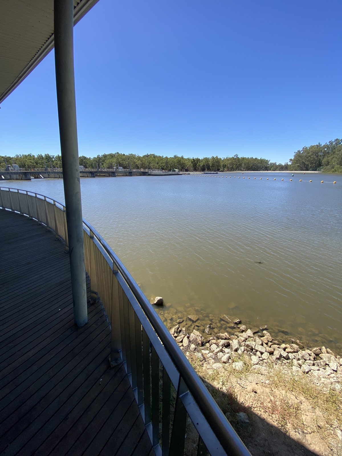 Boardwalk railing overlooking the river and rocky bank at Torrumbarry Weir Holiday Park
