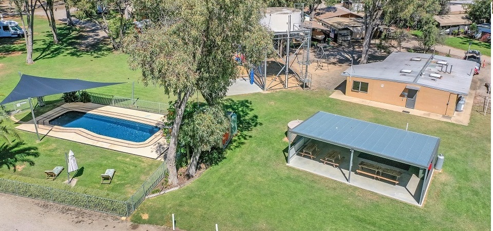 Aerial view of the fenced swimming pool, shaded picnic shelter and amenities block at Torrumbarry Weir Holiday Park in Patho VIC
