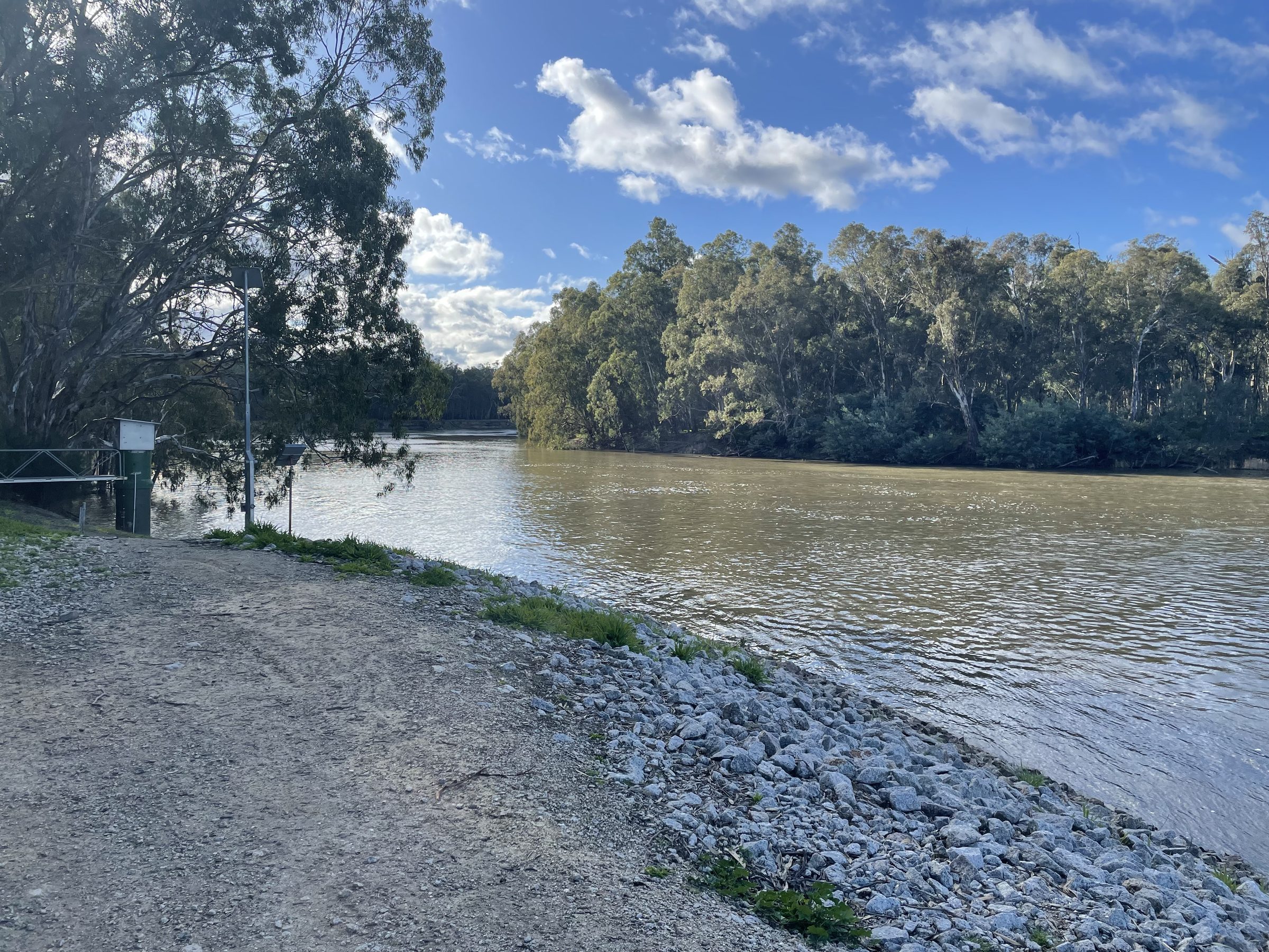 Murray river and gravel bank beneath red gums under blue sky at Torrumbarry Weir Holiday Park