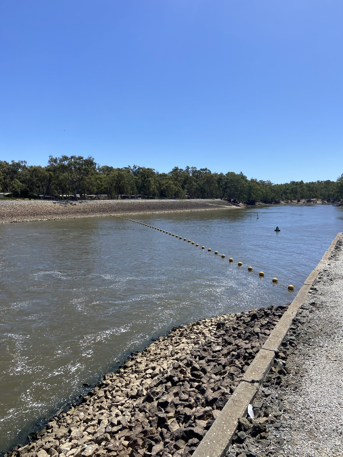 Rock lined bank and buoy line stretching up the murray river at Torrumbarry Weir Holiday Park