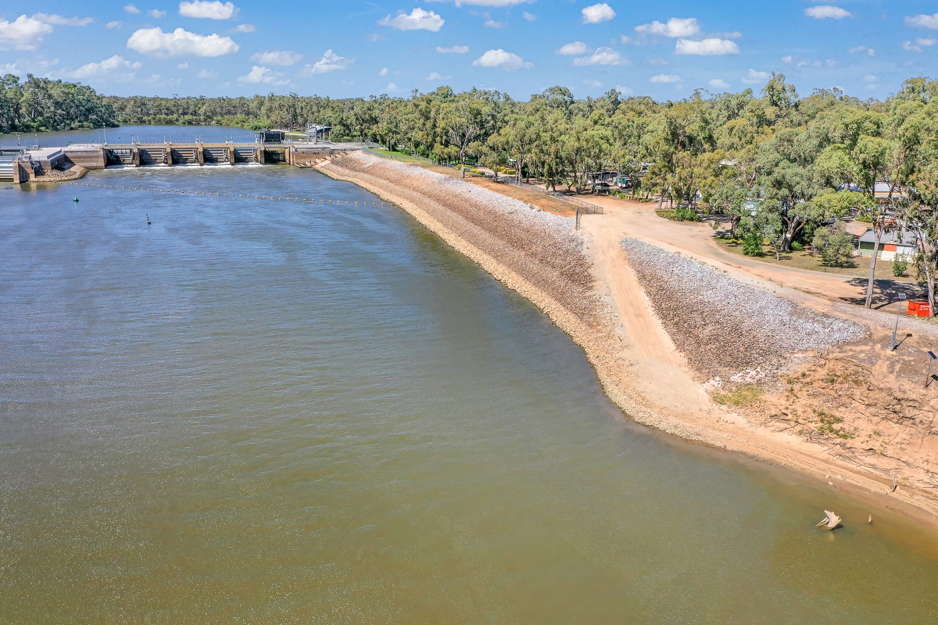 Low aerial of weir wall rock bank and open river water at Torrumbarry Weir Holiday Park