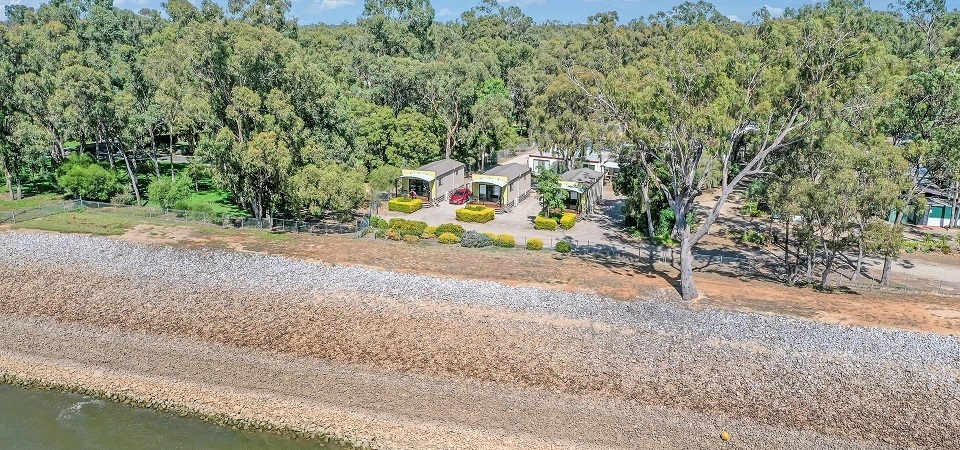 Aerial view of Torrumbarry Weir Holiday Park cabins beside the river bank at Patho VIC, surrounded by native gum trees