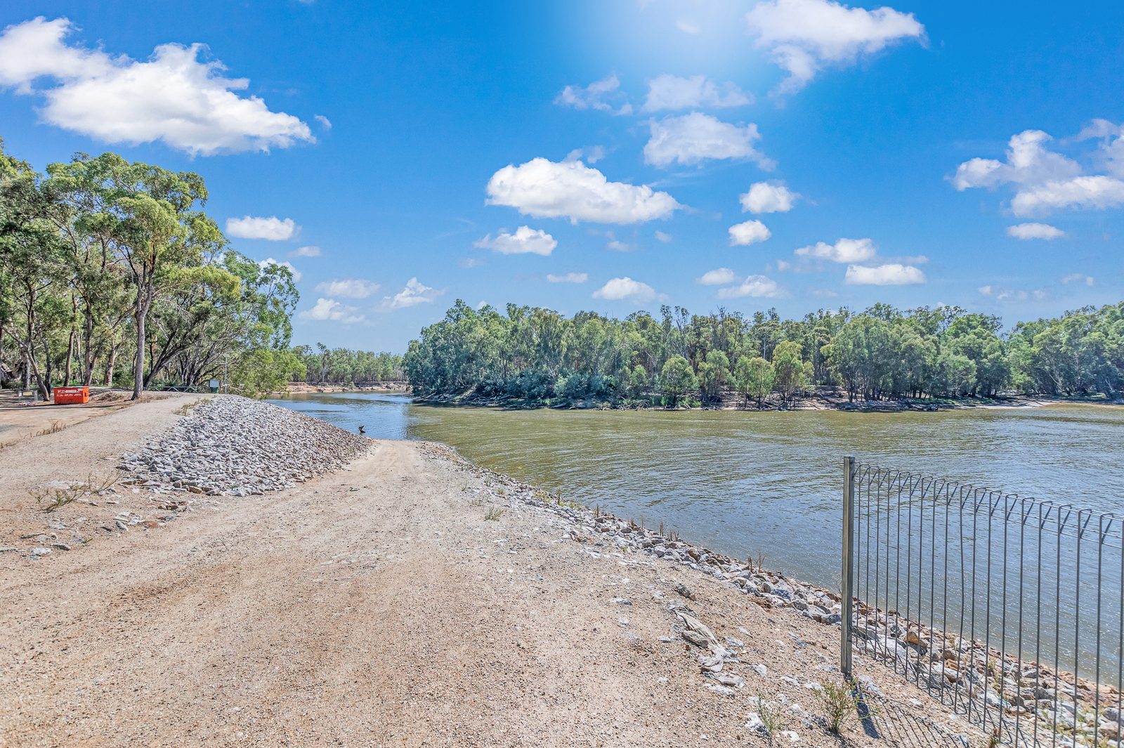 Gravel levee path beside the river with safety fence at Torrumbarry Weir Holiday Park