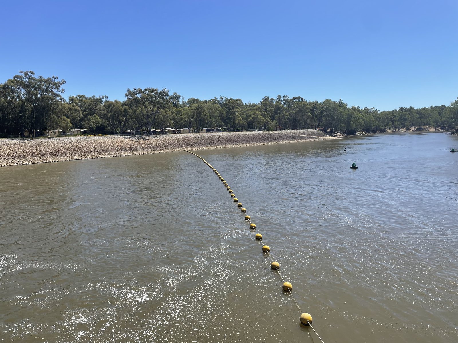 Yellow buoy line strung across the murray river above the weir at Torrumbarry Weir Holiday Park
