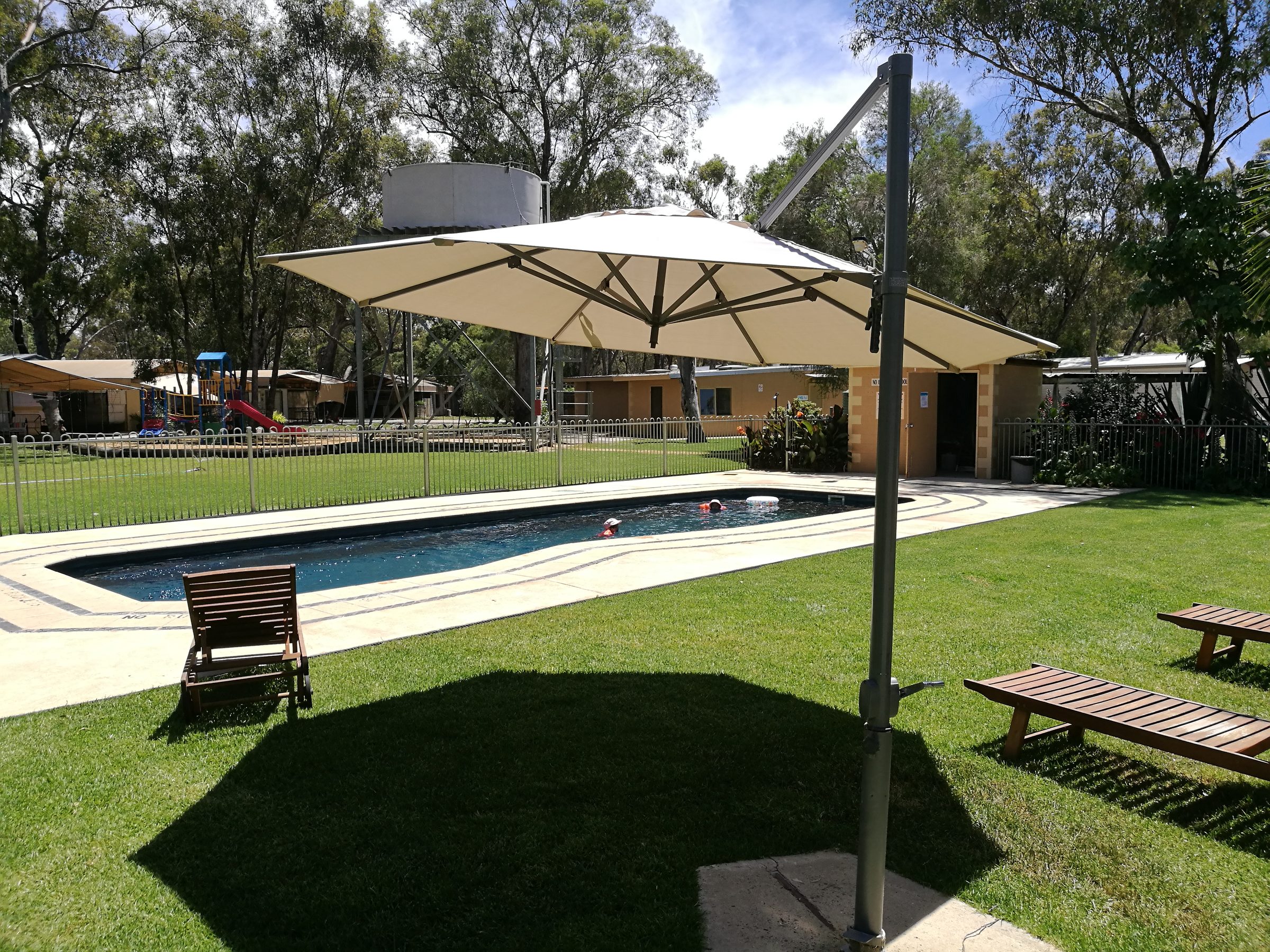 Pool with large cantilever shade umbrella lounger and picnic table at Torrumbarry Weir Holiday Park
