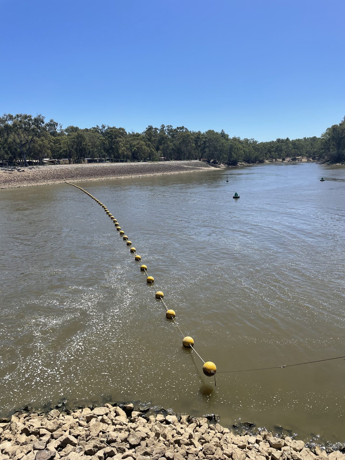 Buoy line and rocky river bank looking upstream to the weir at Torrumbarry Weir Holiday Park